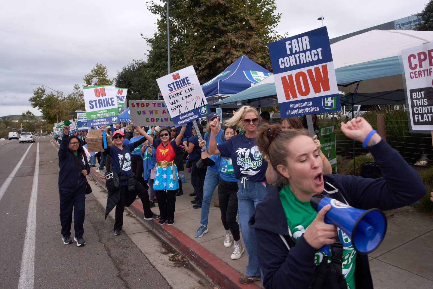 Kaiser Permanente health care workers hold signs and chant slogans while on strike in front of the Kaiser Permanente San Diego Medical Center Tuesday, Oct. 14, 2025, in San Diego.
