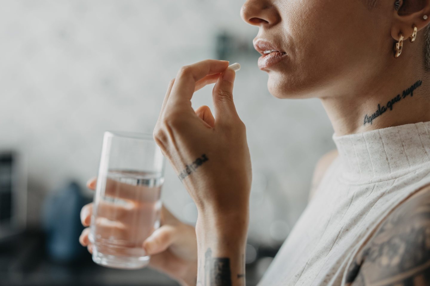 Woman taking a pill and holding a glass of water