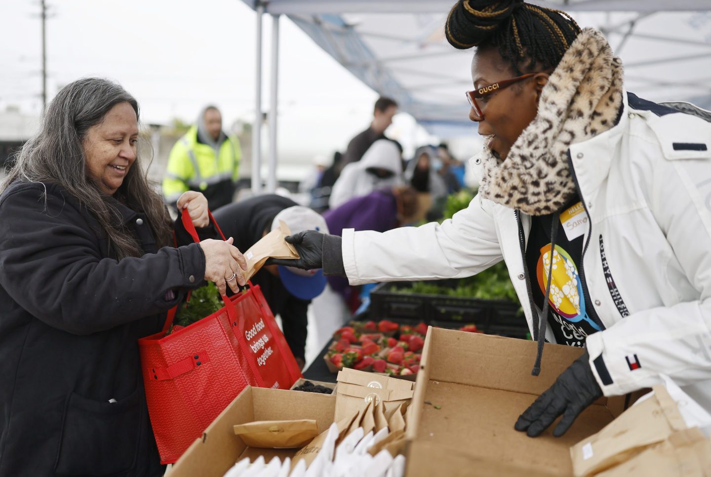 ALTADENA, CALIFORNIA - MARCH 14: A volunteer (R) passes out free cookies as community members receive free produce near World Central Kitchen's new Rapid Response Mobile Kitchen near the Eaton Fire burn zone on March 14, 2025 in Altadena, California. The 43-foot-long truck can produce up to 20,000 meals a day to disaster-impacted communities and was on its first disaster response cooking mission today in Altadena. (Photo by Mario Tama/Getty Images)